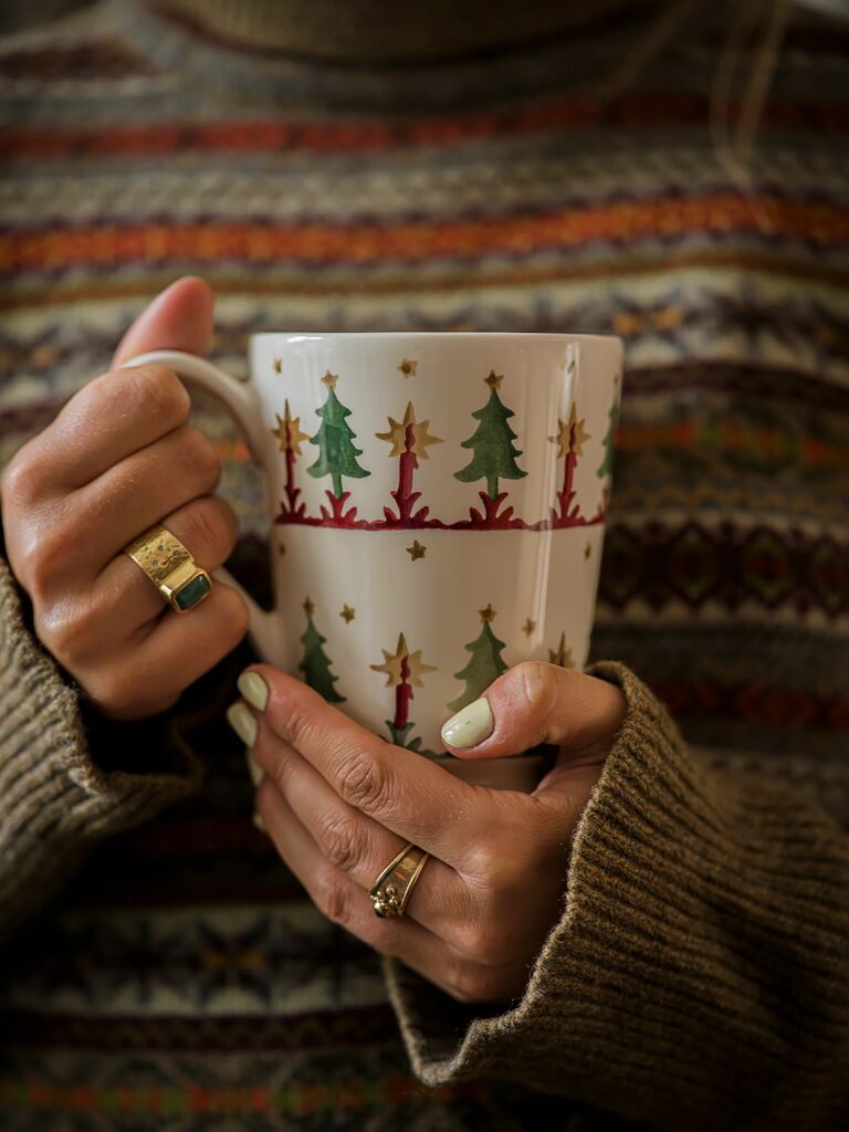 Ceramic mugs with red heart and blue star patterns, labeled "½ Pint Mug" and "Cocoa Mug," on wooden shelf.