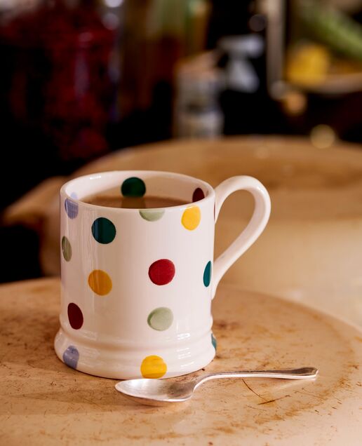 Colourful polka dot tea pot and a matching personalised name mug placed on a wooden table. Bright and colourful tableware inspiration.