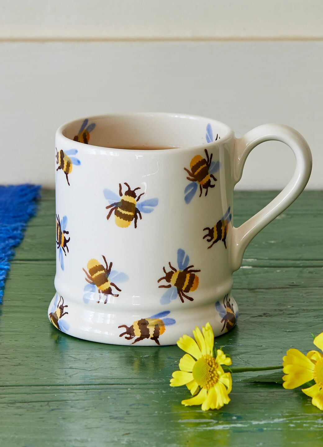 Ceramic mug with hand-painted bee pattern, featuring a classic white glaze and vibrant yellow and blue accents.